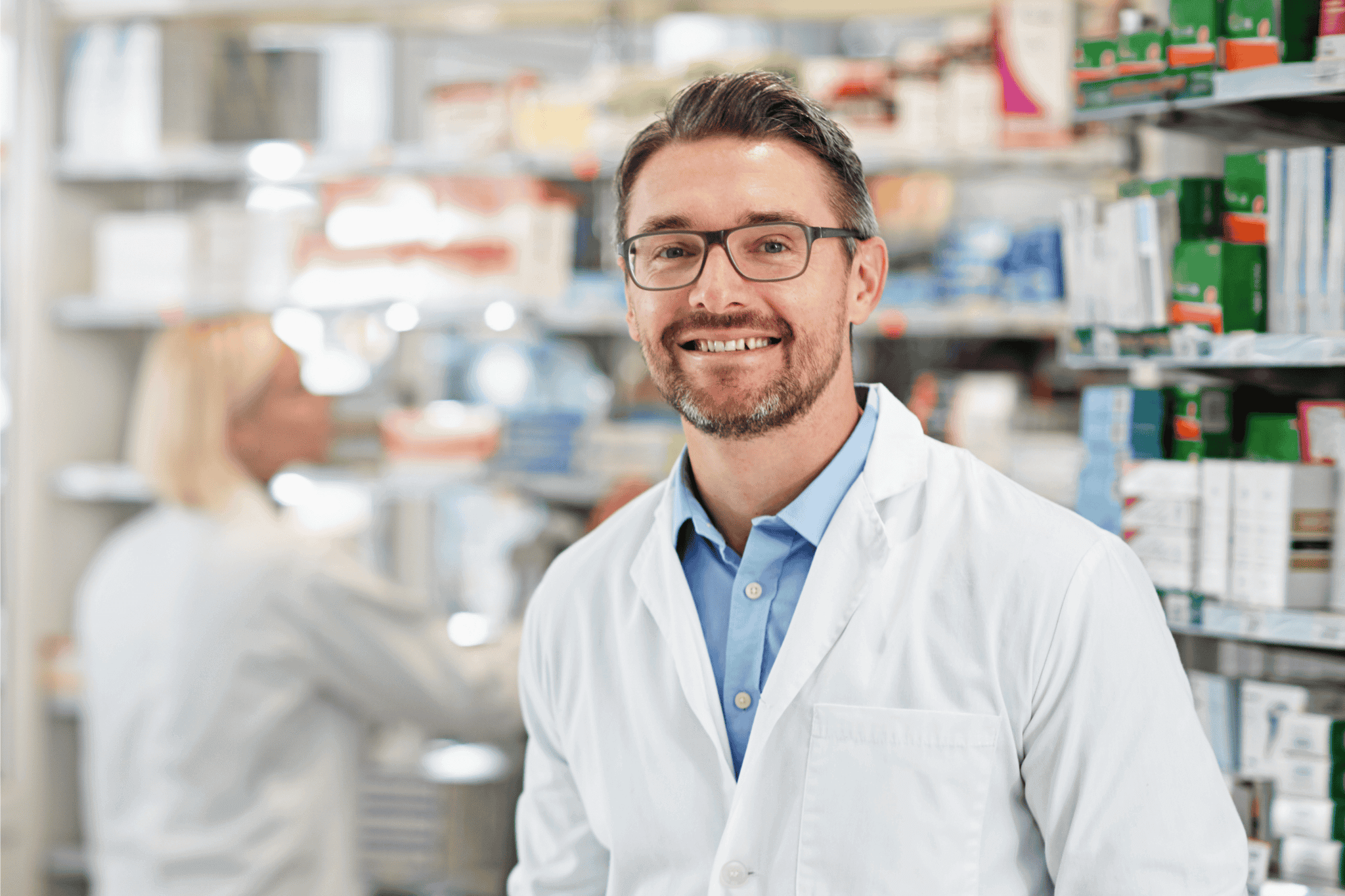 Smiling pharmacist in white coat at pharmacy